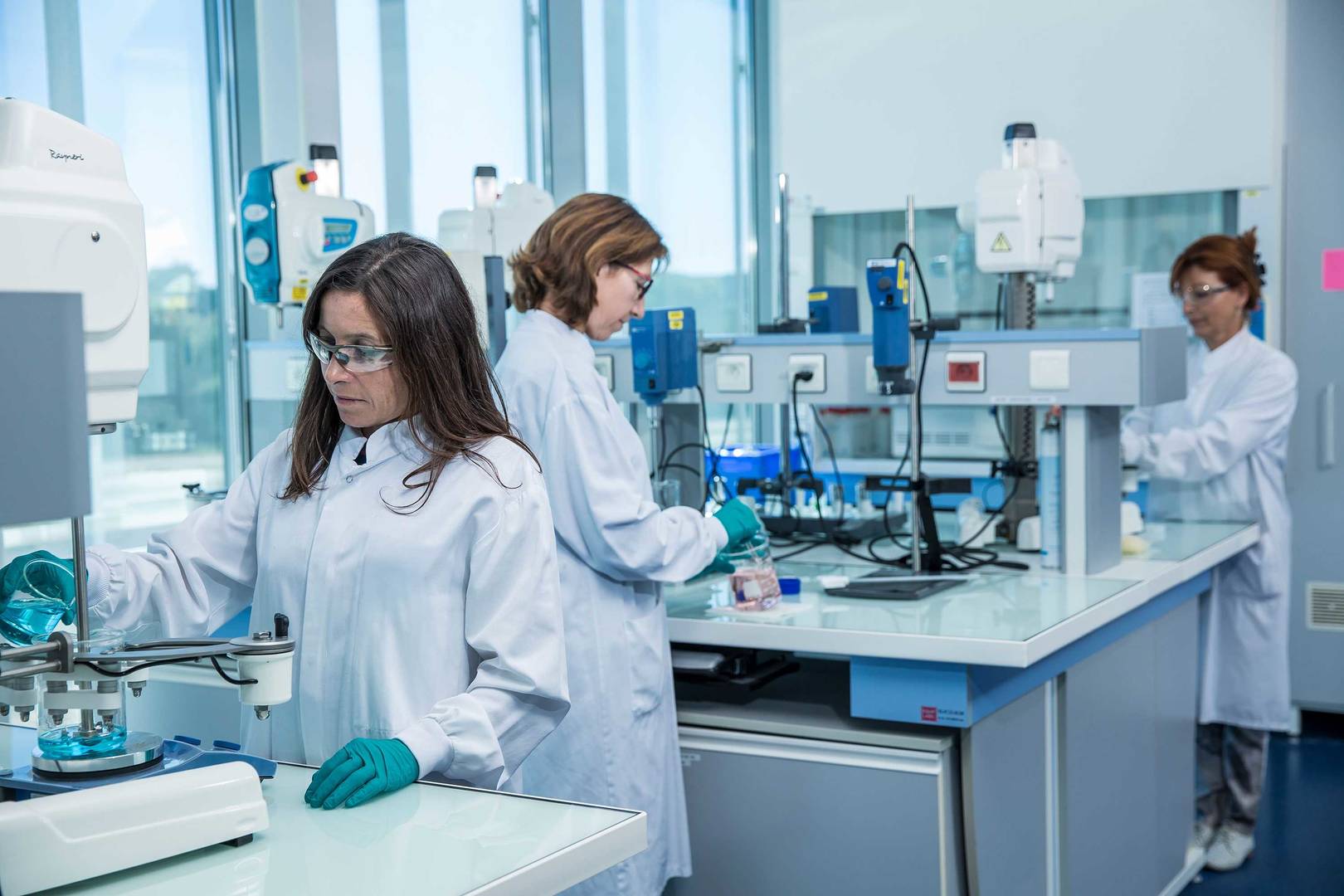 Three female scientists wearing lab coats are working in a formulation lab