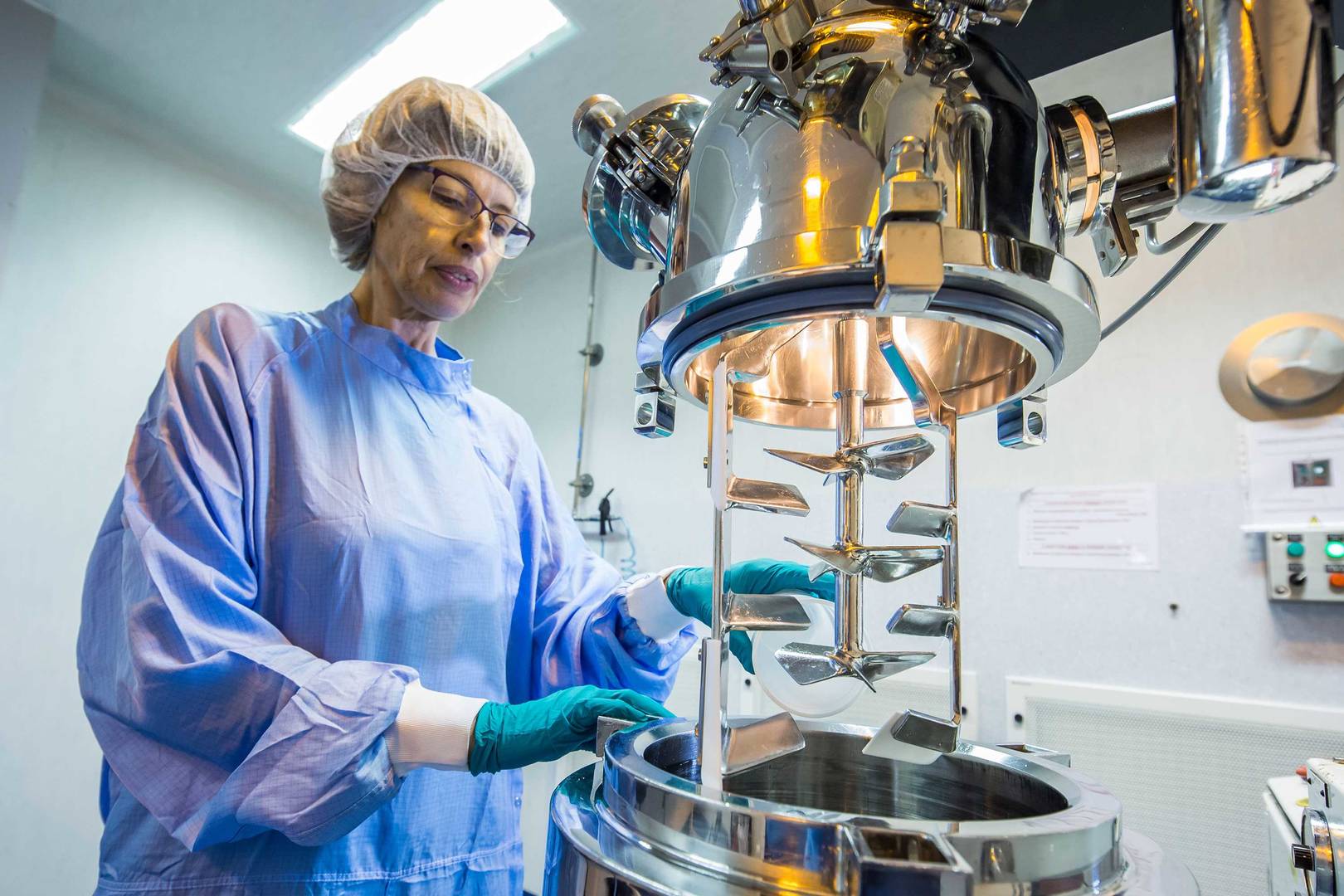 A scientist is pouring powder into a manufacturing vessel