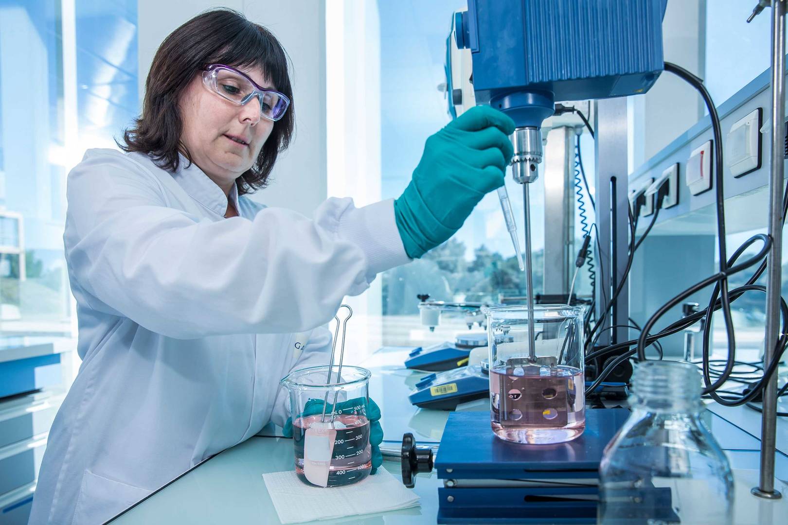 Formulation scientist preparing a light pink solution using a typical lab-scale mixer