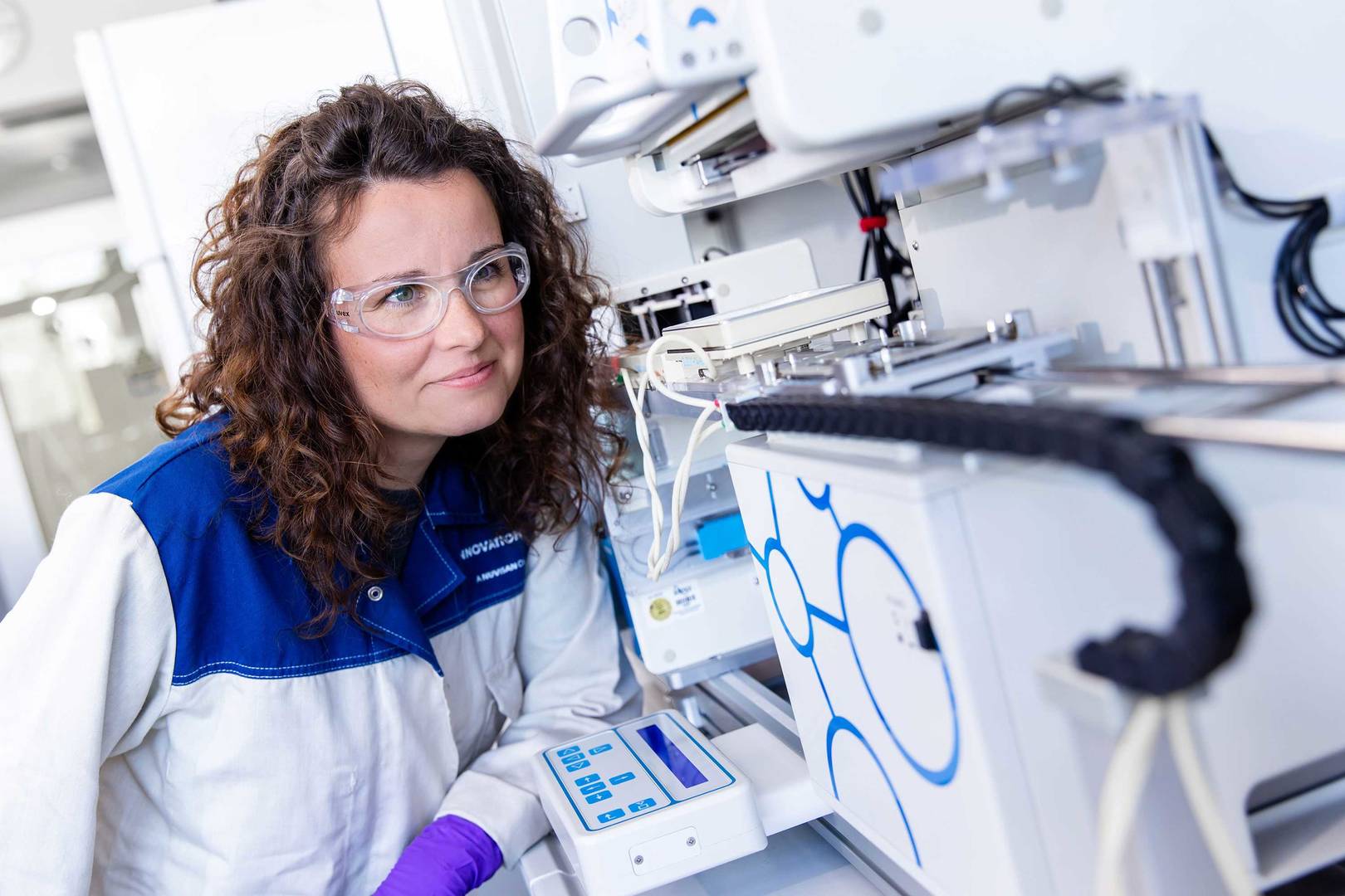 Scientist in a labcoat inspecting an HTS robot 