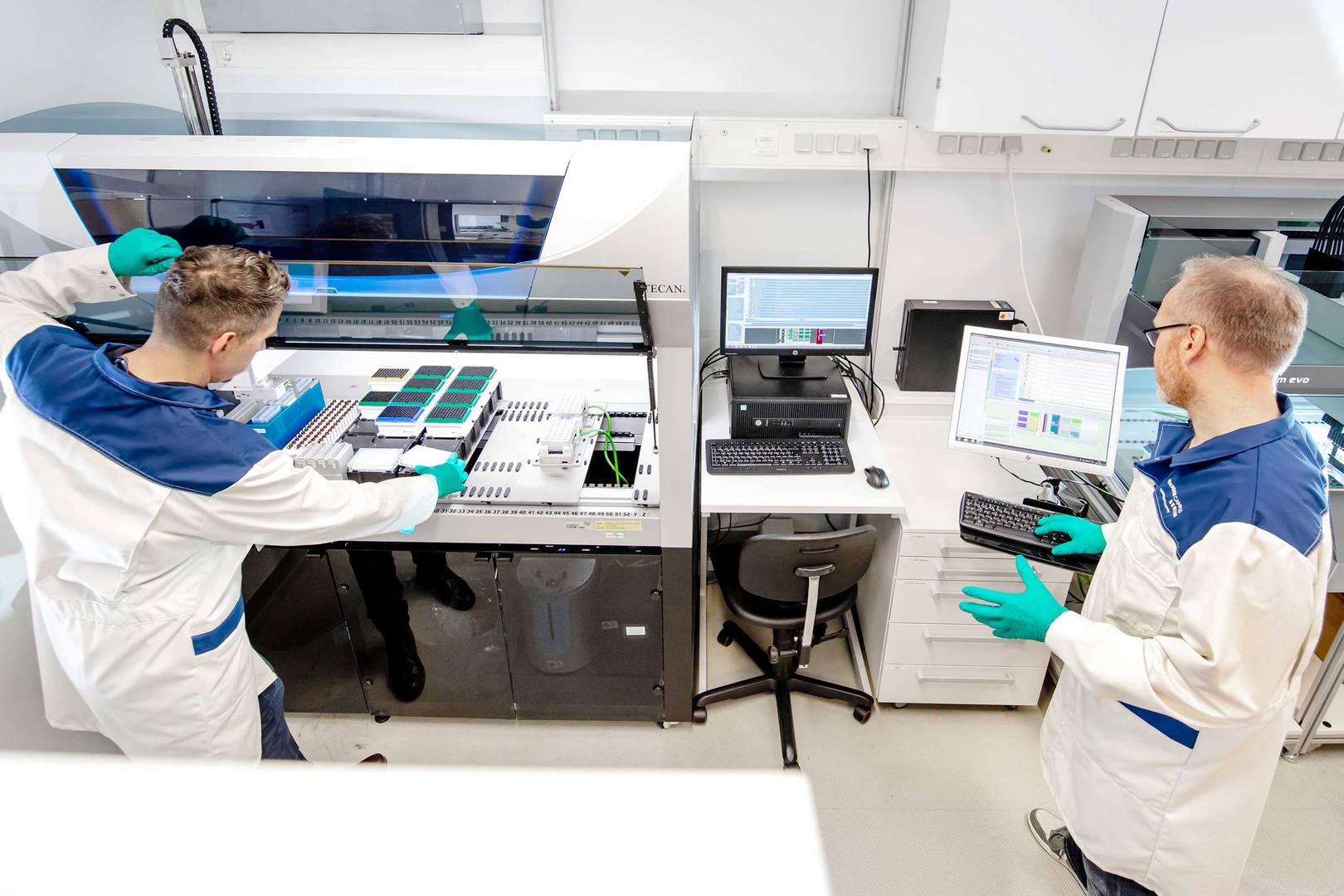 Two scientists operating a large liquid handling machine