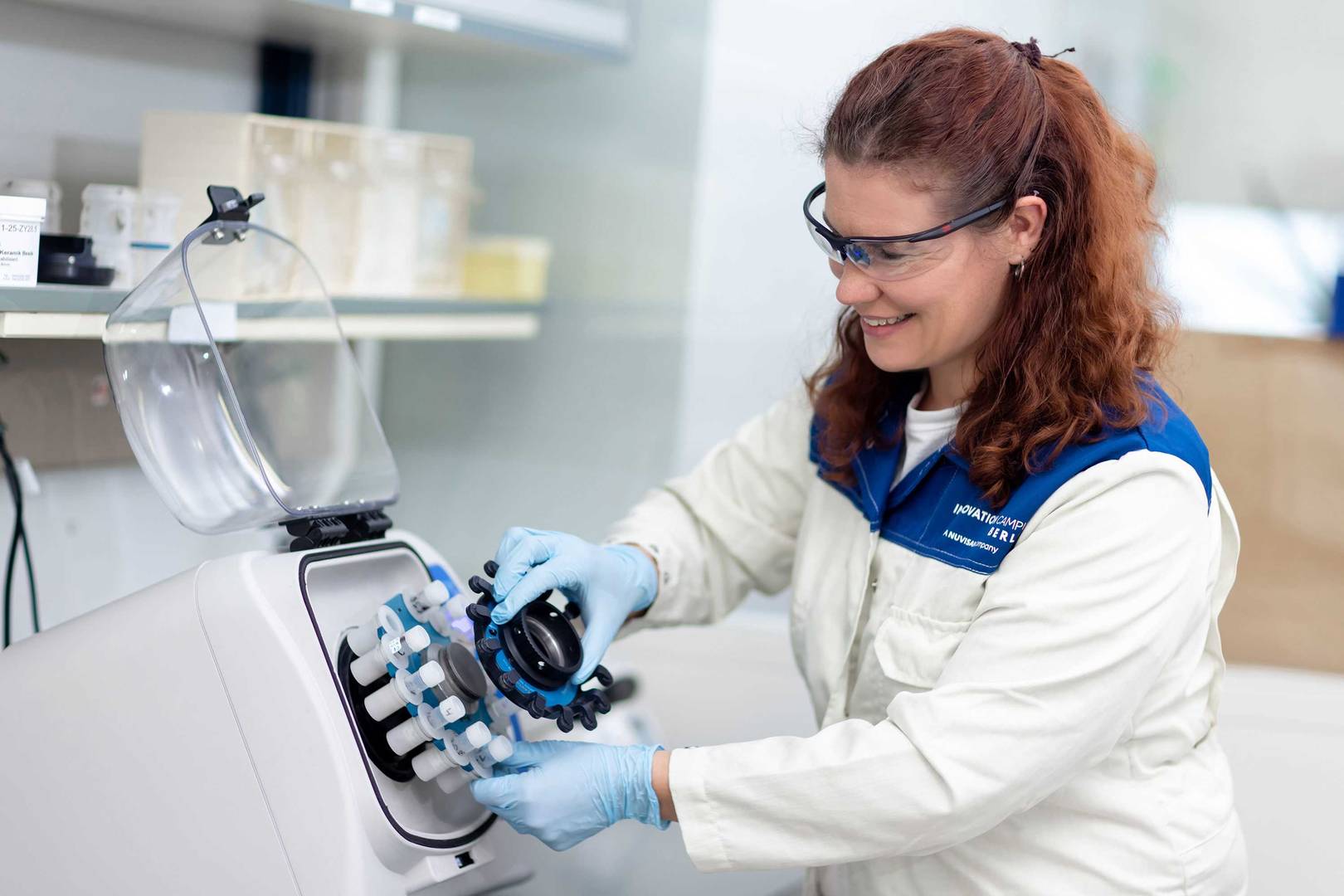 Female scientist wearing lab goggles operating a speedvac machine