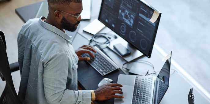 High-angle view of software developer working on computers and data systems in office