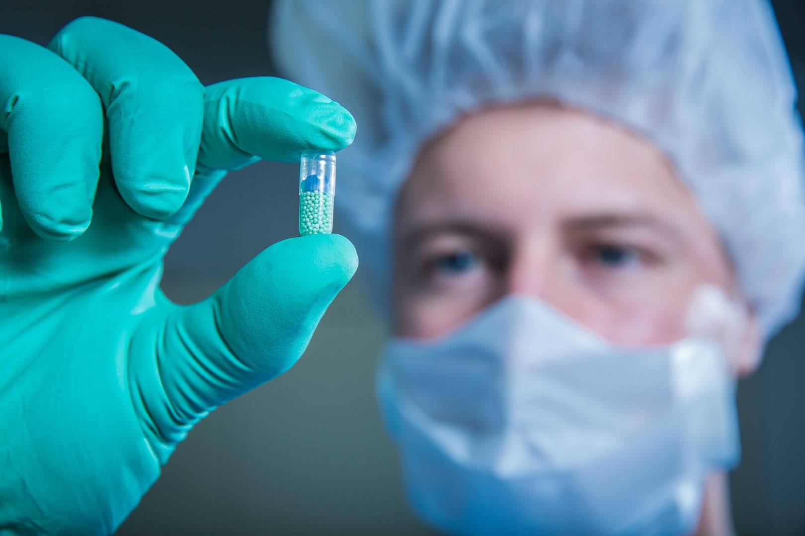 Scientist wearing gloves holding pills in a laboratory setting