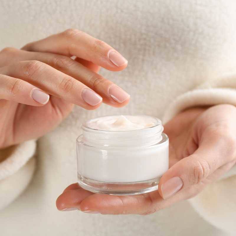 Close-up of a woman holding a jar of moisturizing cream